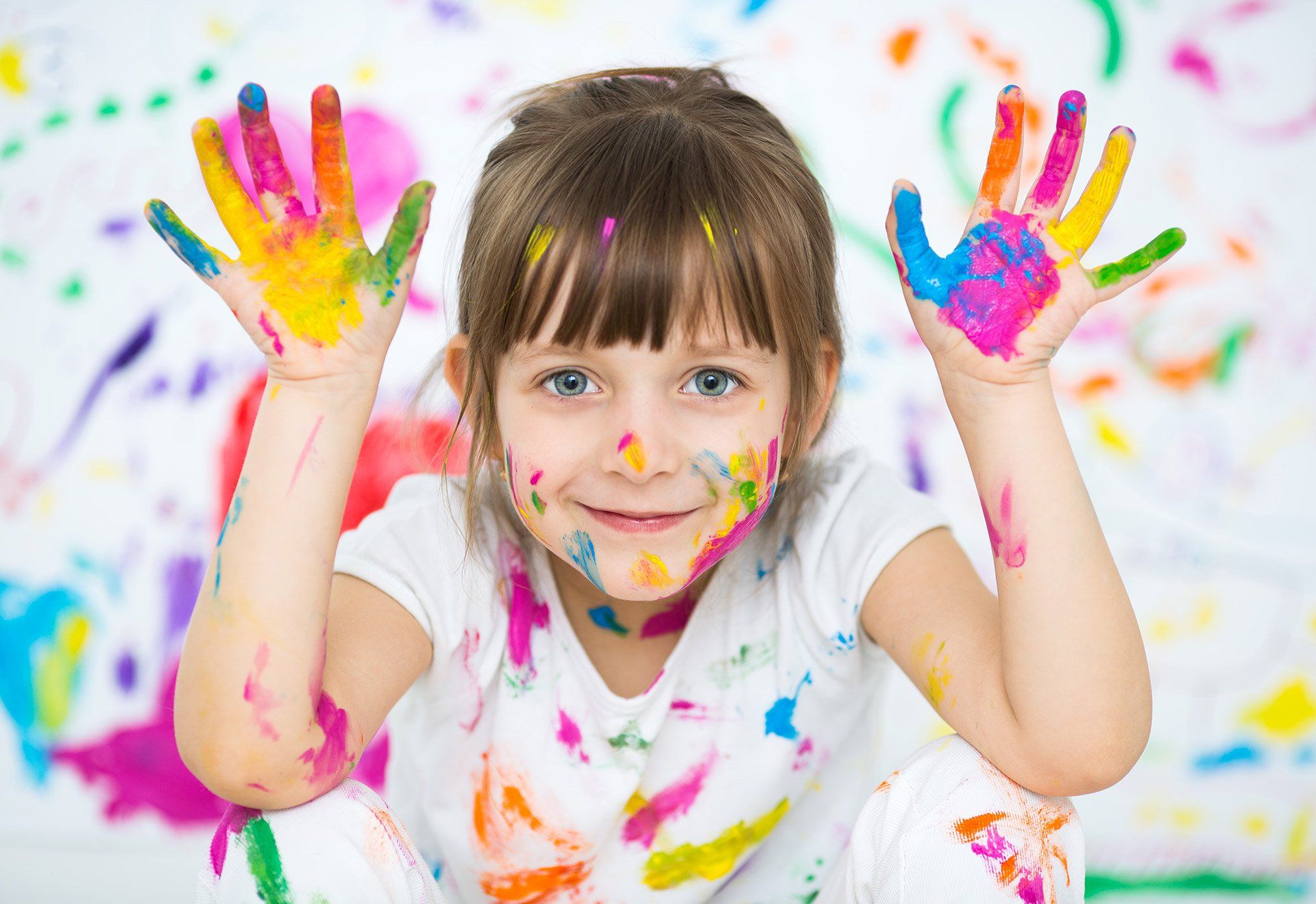 Criança sorrindo com as mãos pintadas